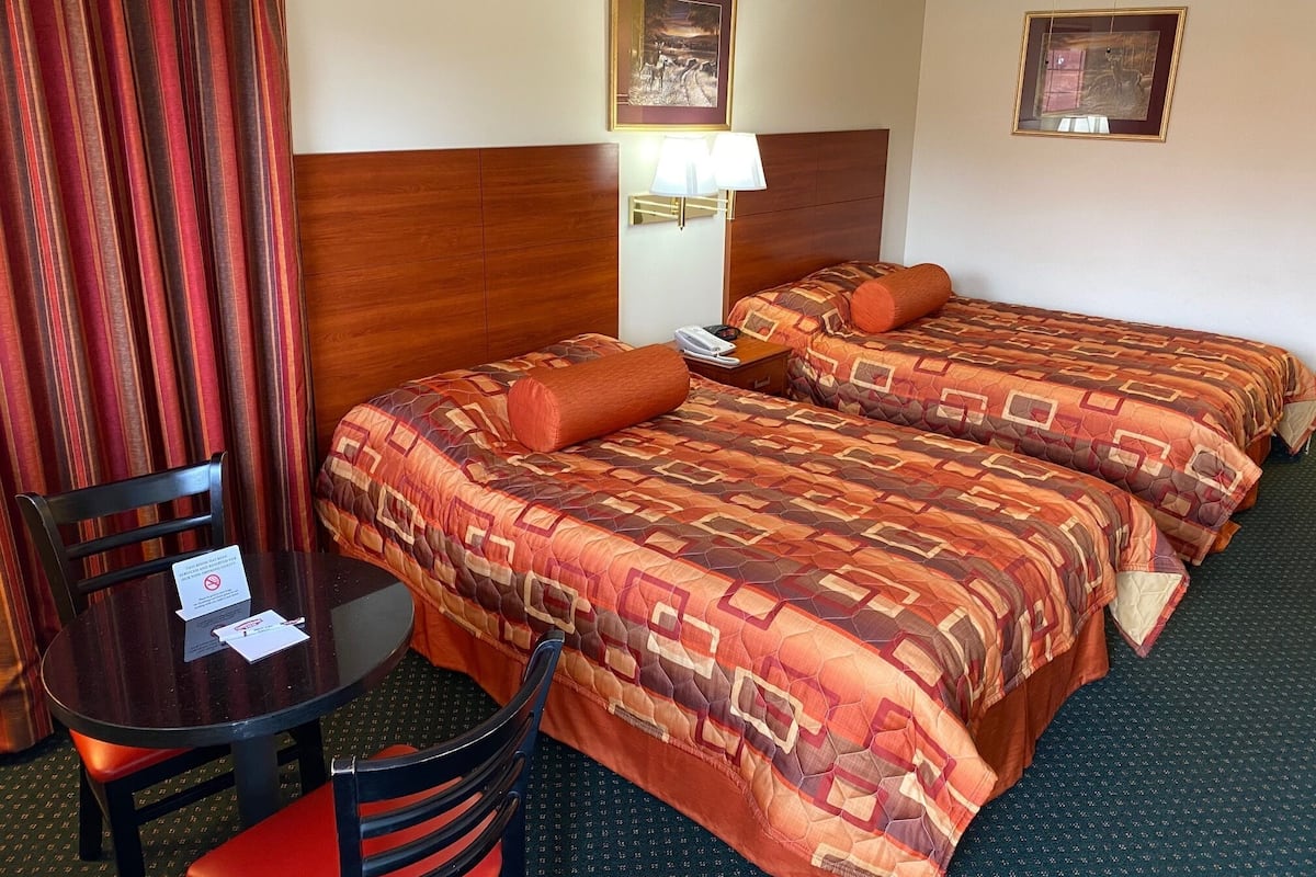 Une chambre d’hôtel avec deux lits, un bureau, une chaise et une table.