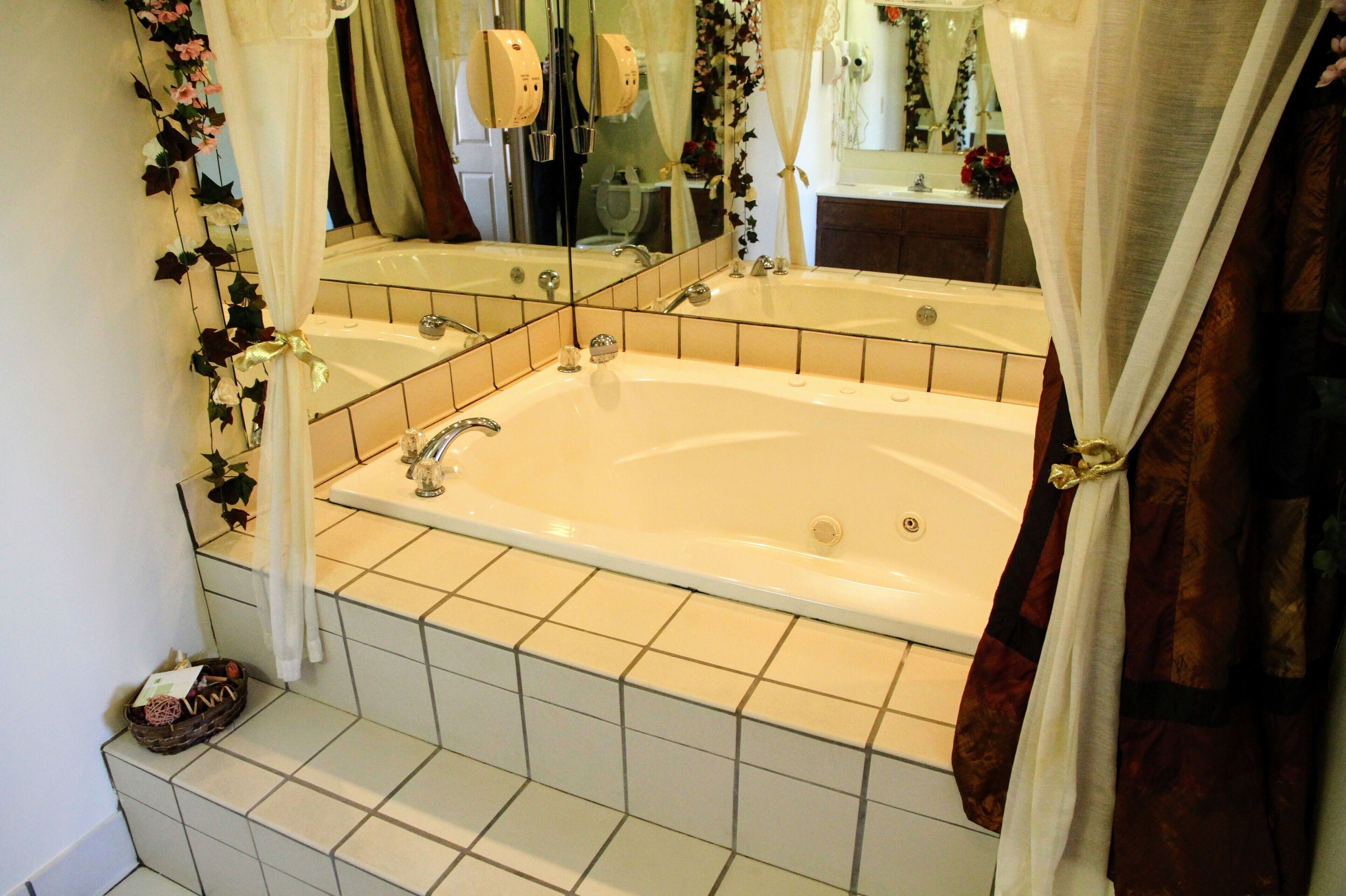 A bathroom with a large bathtub, a mirror, and a shower area.