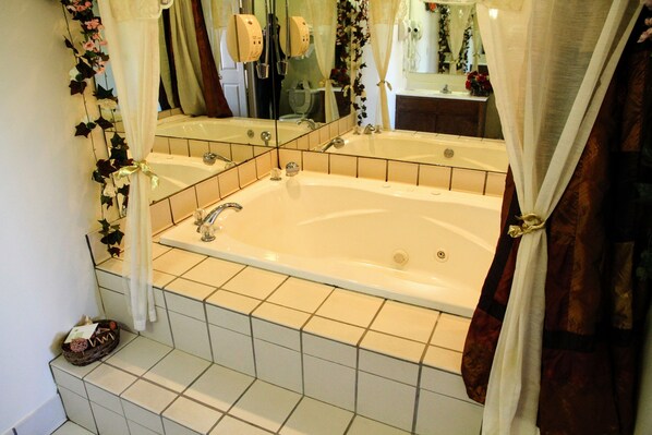 Un baño con una bañera grande, un espejo y zona de ducha.