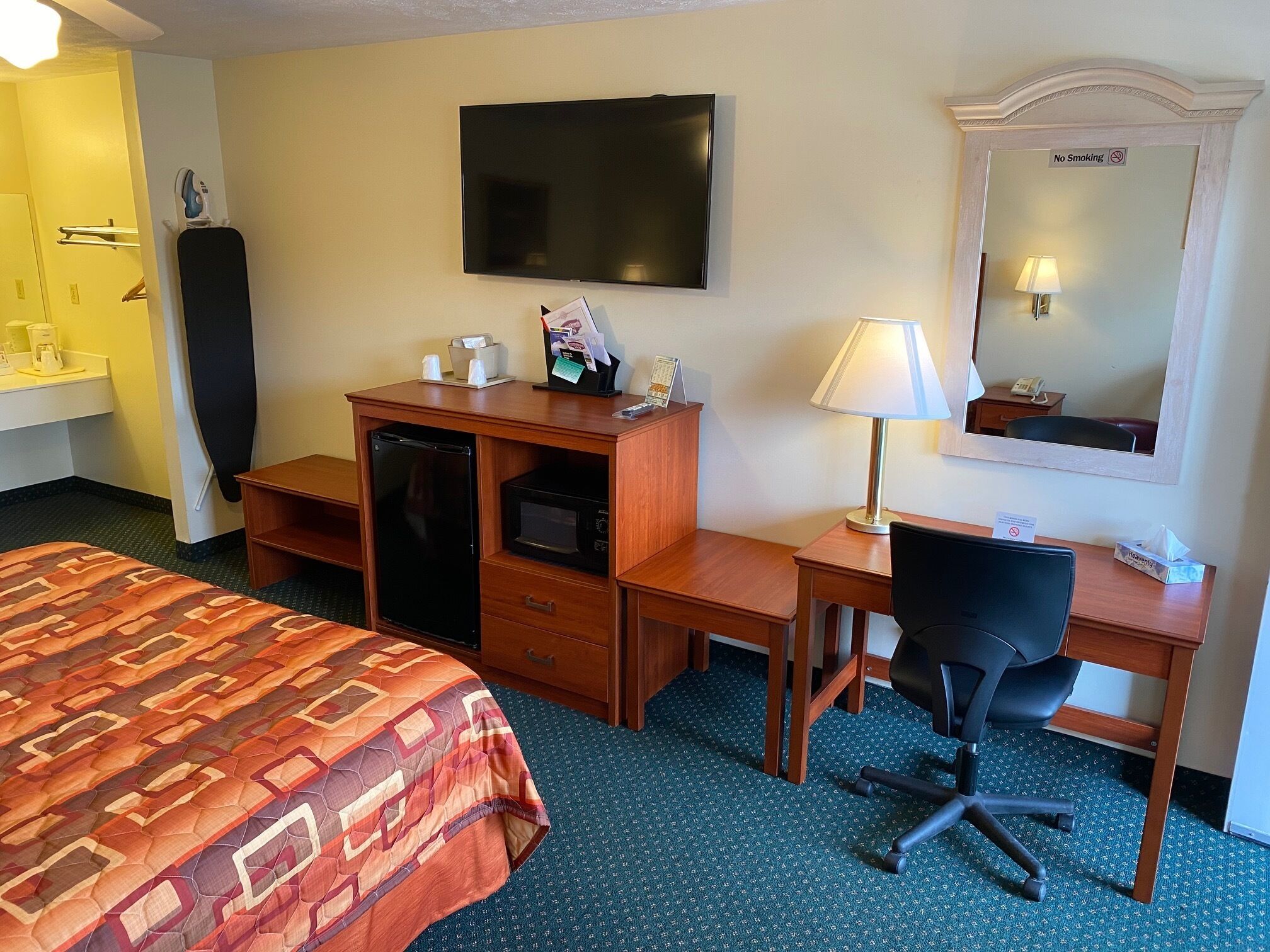 Habitación de hotel con cama, escritorio, silla, televisor, microondas y un letrero de no fumar.