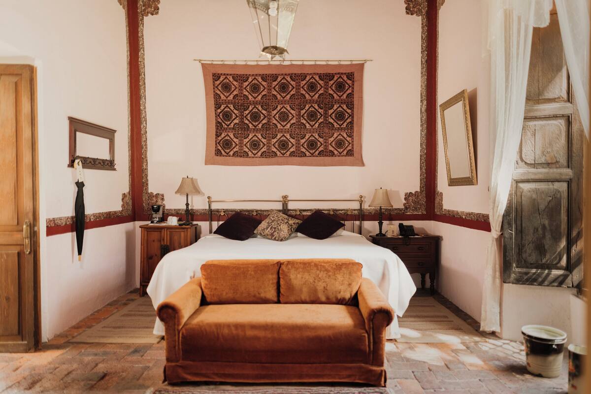 Ein Schlafzimmer mit einem großen Bett, einer hölzernen Bank, einem Wandteppich und einer Holztür.