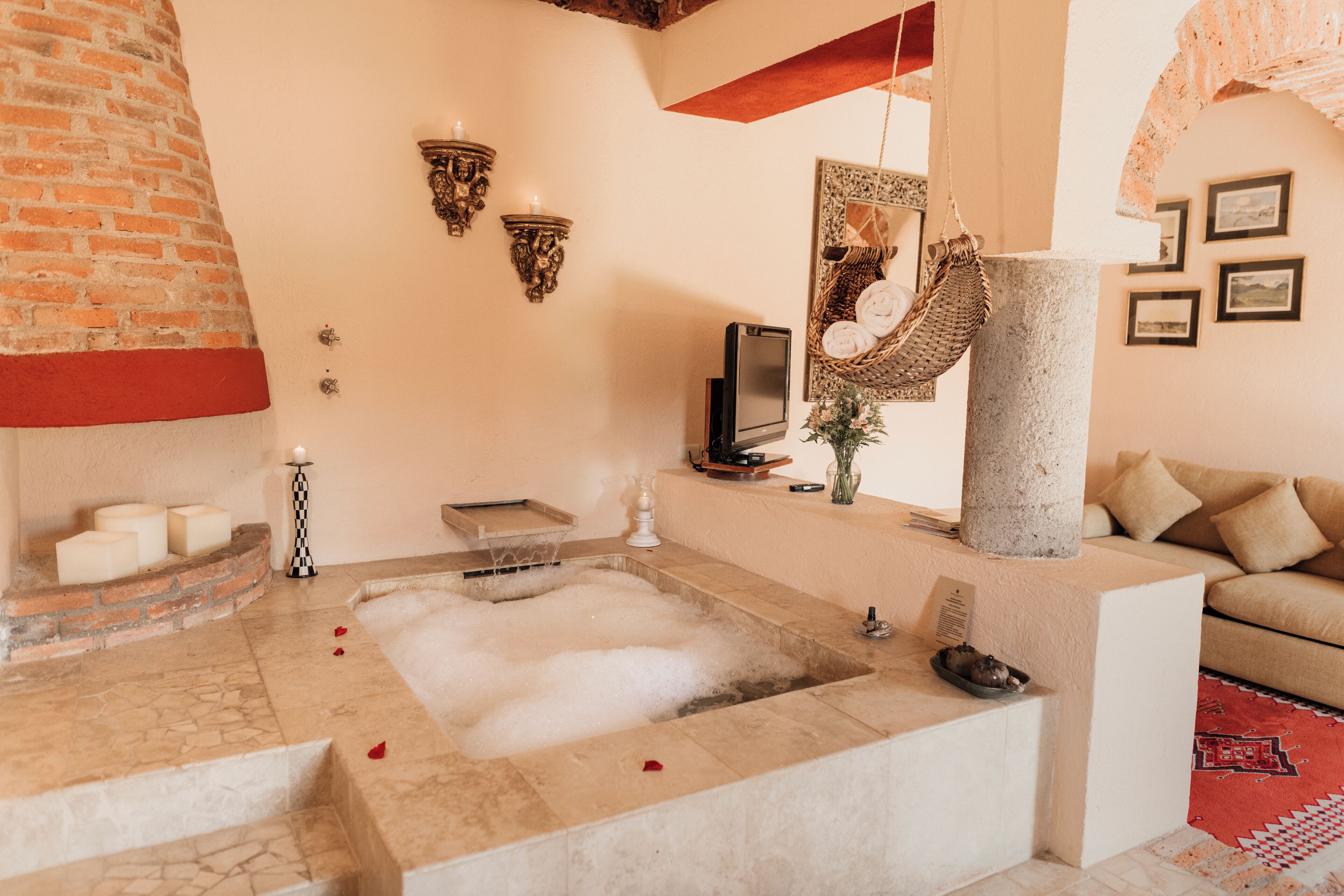 A spa area with a stone bathtub, a brick wall, and a beige sofa.