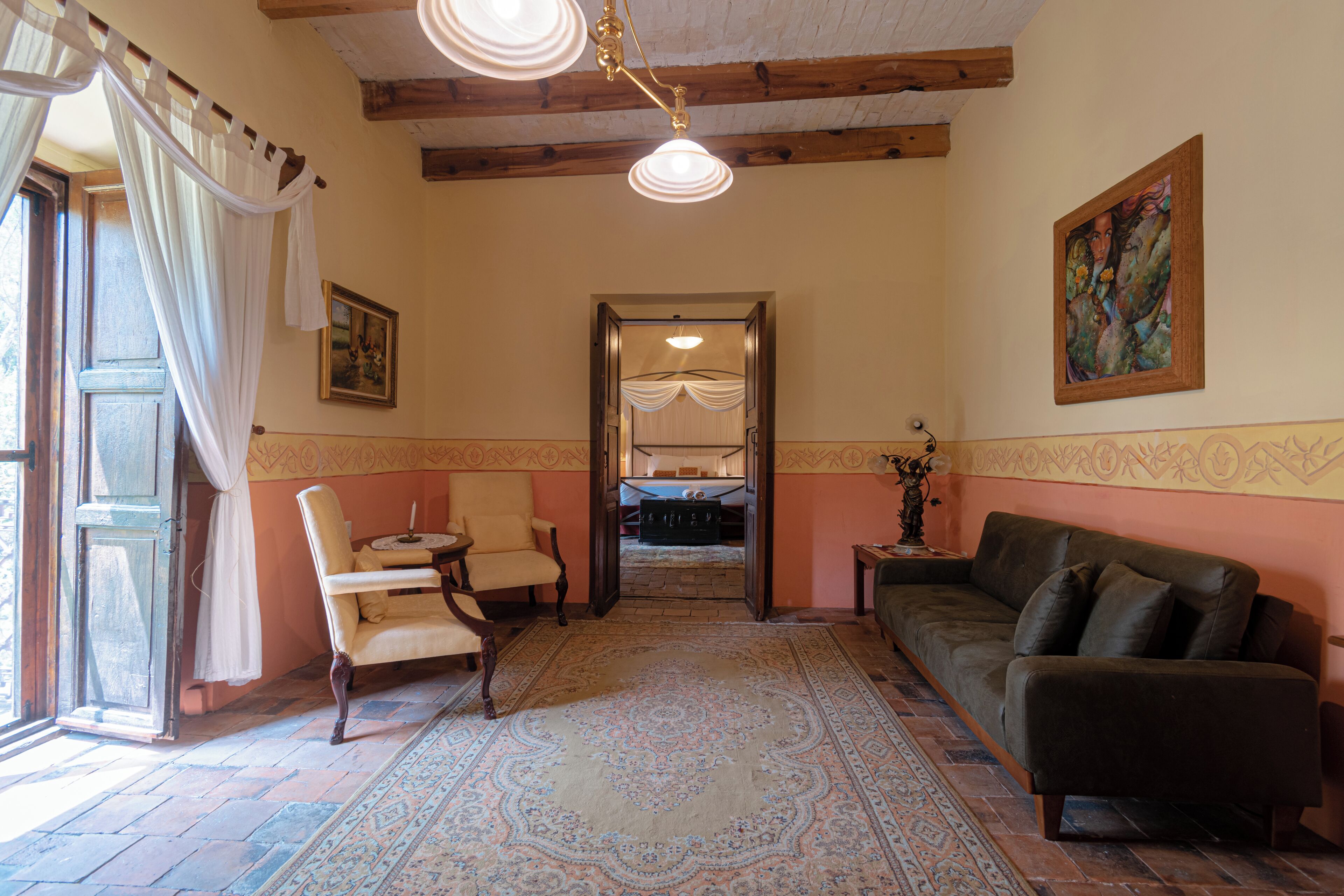 A room with a large rug, a sofa, a chair, a table, and a painting on the wall.