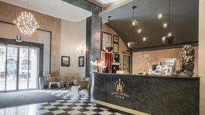 A hotel lobby with a checkered floor, a reception desk, and modern lighting fixtures. - Hotel Impero (Cremona)