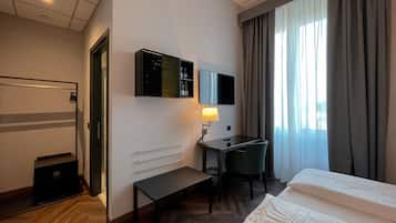 Habitación de hotel con cama, escritorio, silla y televisor en la pared.