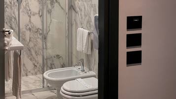 A bathroom with a bidet, toilet, and a mirror.