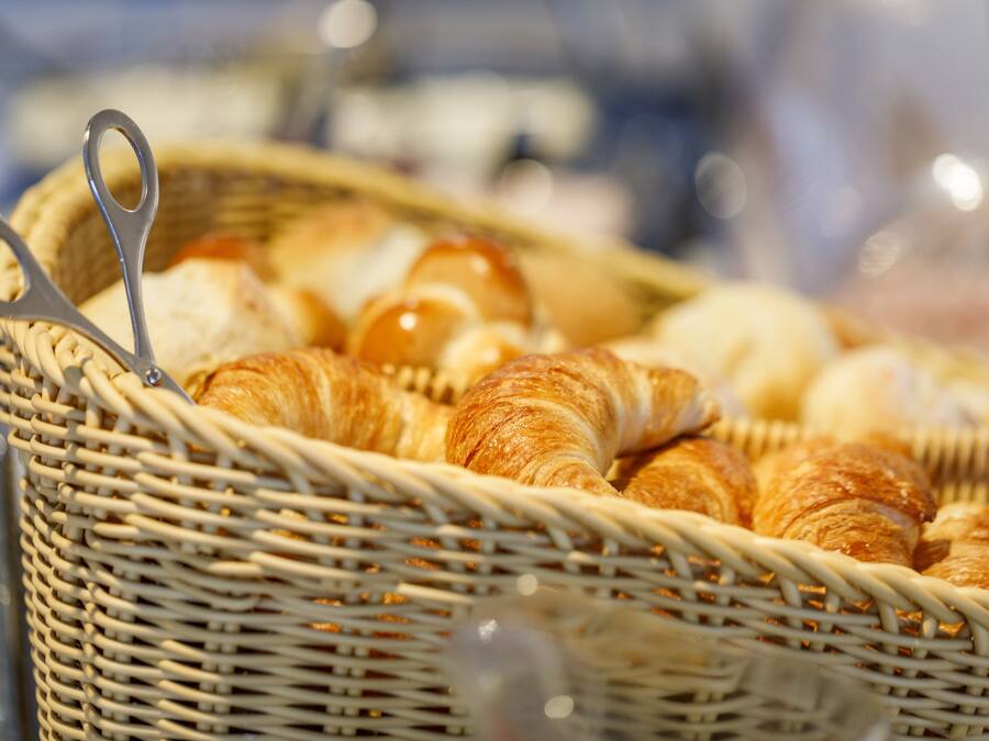Ein Korbwicker-Korb gefüllt mit Croissants und einer Schere.