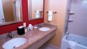 A bathroom with two sinks, a mirror, a shower, and a towel rack.
