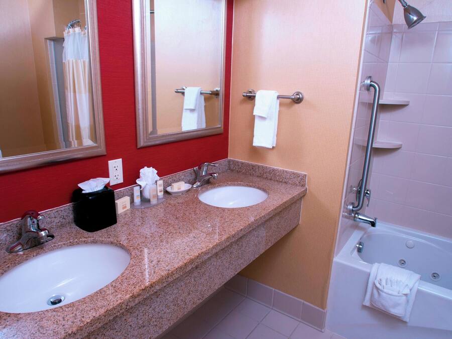 Ein Badezimmer mit zwei Waschbecken, einem Spiegel, einer Dusche und einem Handtuchhalter.