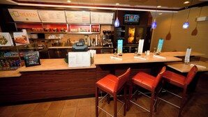 Ein Restaurantinneres mit Barbereich, hölzernen Barhocker und einer Speisekarte.