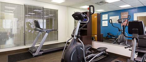 Une salle de sport équipée de tapis de course, d’un appareil elliptique et d’un mur recouvert de miroirs.