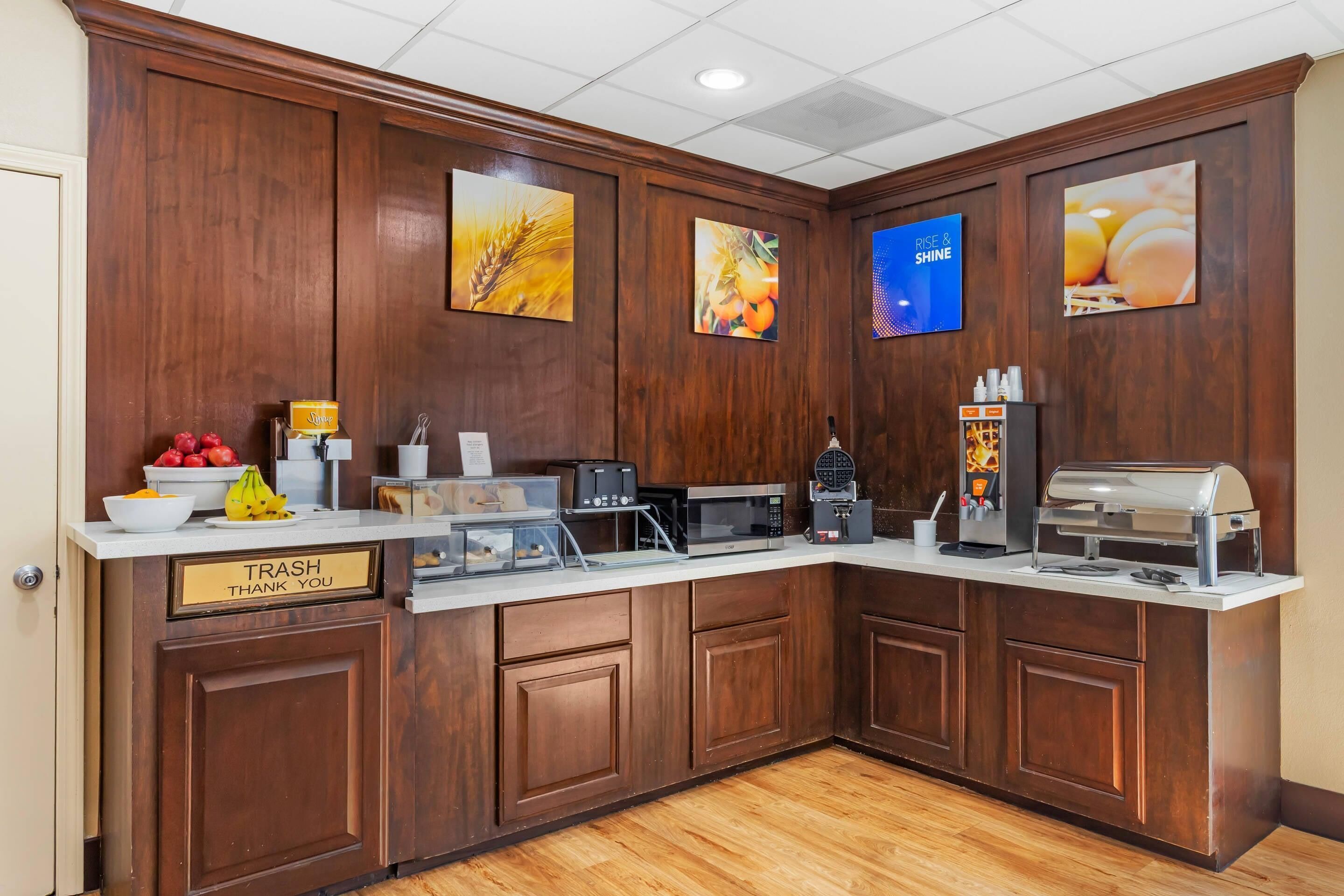 A kitchen area with a trash bin, microwave, coffee machine, and a grill.