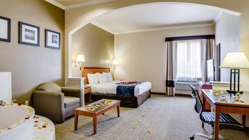 A hotel room with a bed, a desk, a chair, a sofa, a bathroom with a bathtub, and a large window with curtains.