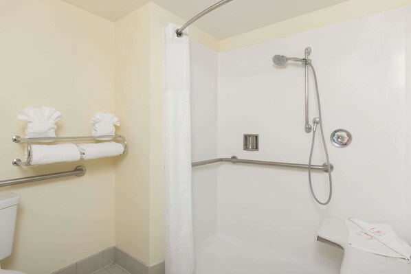 Un baño con ducha, barras de apoyo y un inodoro.