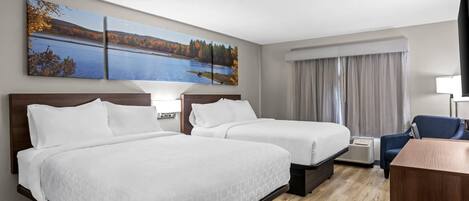 A hotel room with two beds, a desk, a chair, a large window with curtains, and a painting of a lake.