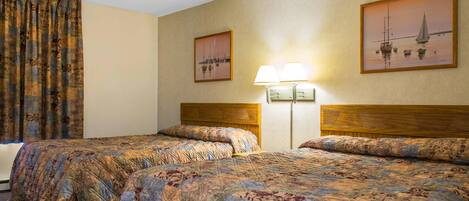 A hotel room with two beds, a window with curtains, and two wall-mounted lamps.