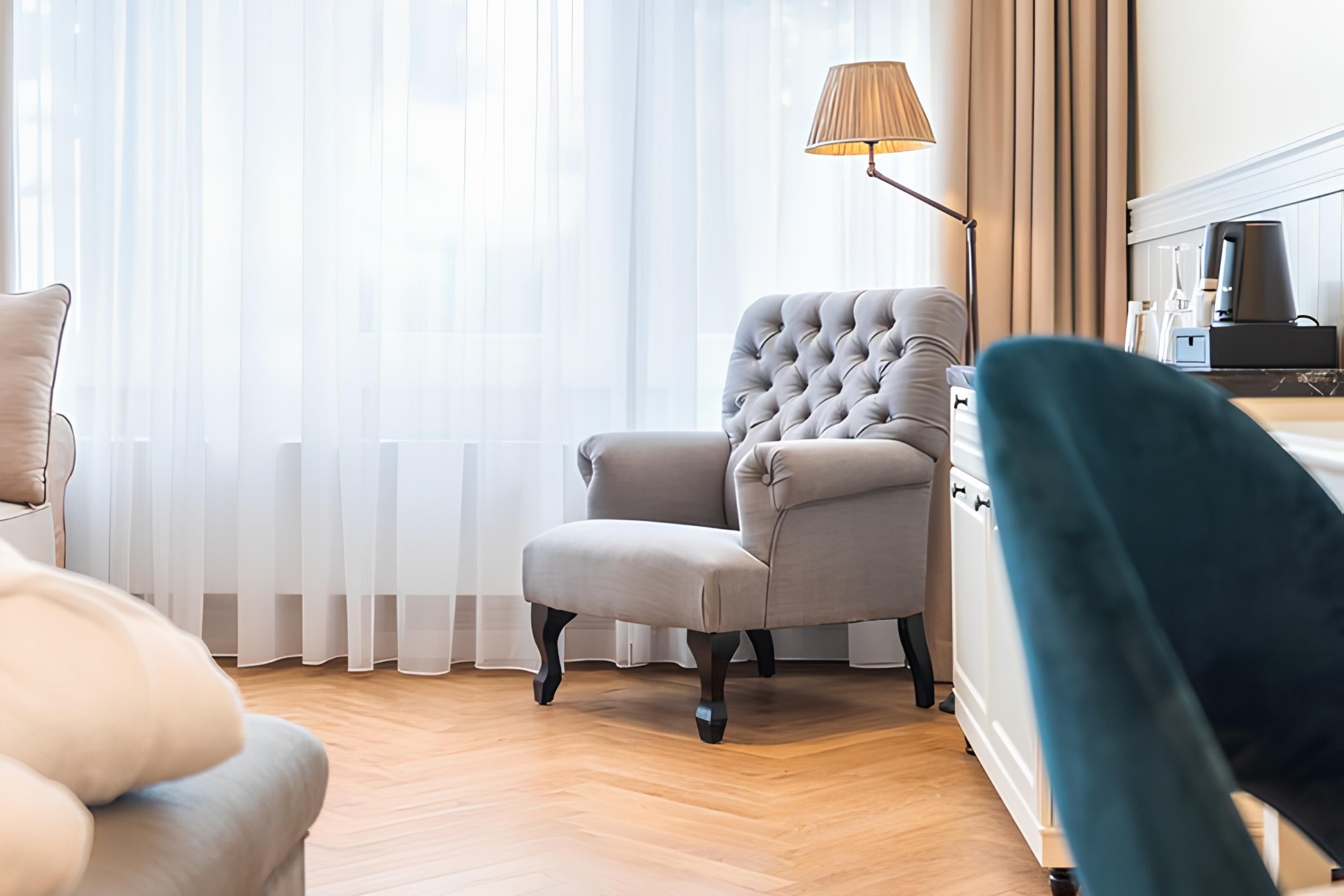 A room with a tufted armchair, a lamp, a bed, and a radiator.