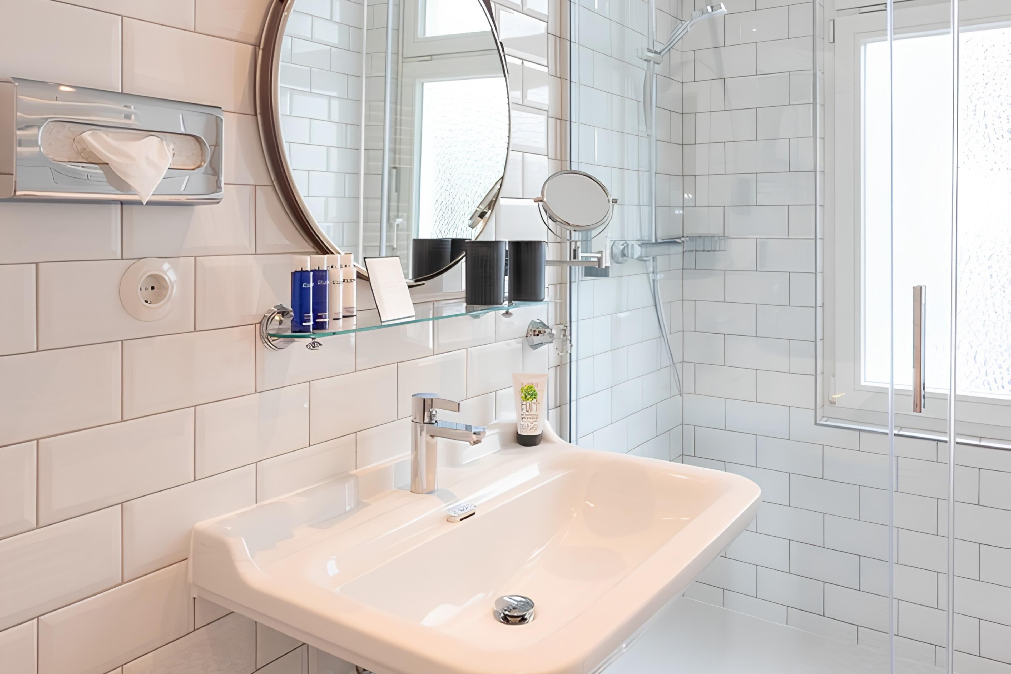 A modern bathroom with a large sink, a mirror, and a shower area.