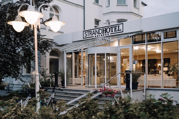 A hotel entrance with a sign reading 'STRANDHOTEL AHLBECK,' a covered entrance, and a staircase leading up. - Strandhotel Ahlbeck, a member of Radisson Individuals (Heringsdorf)