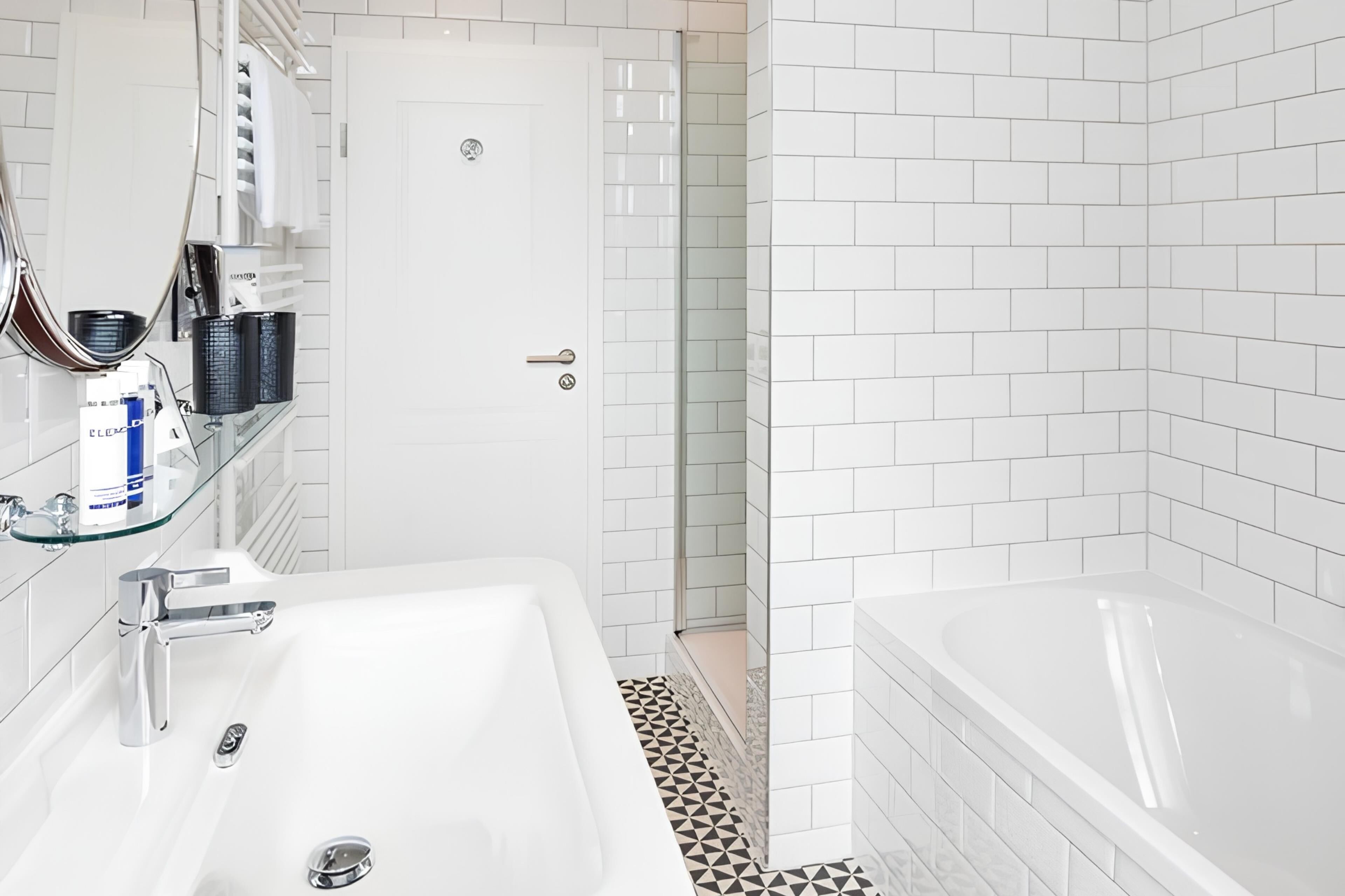 A modern bathroom with a white sink, a bathtub, and a glass shower enclosure.