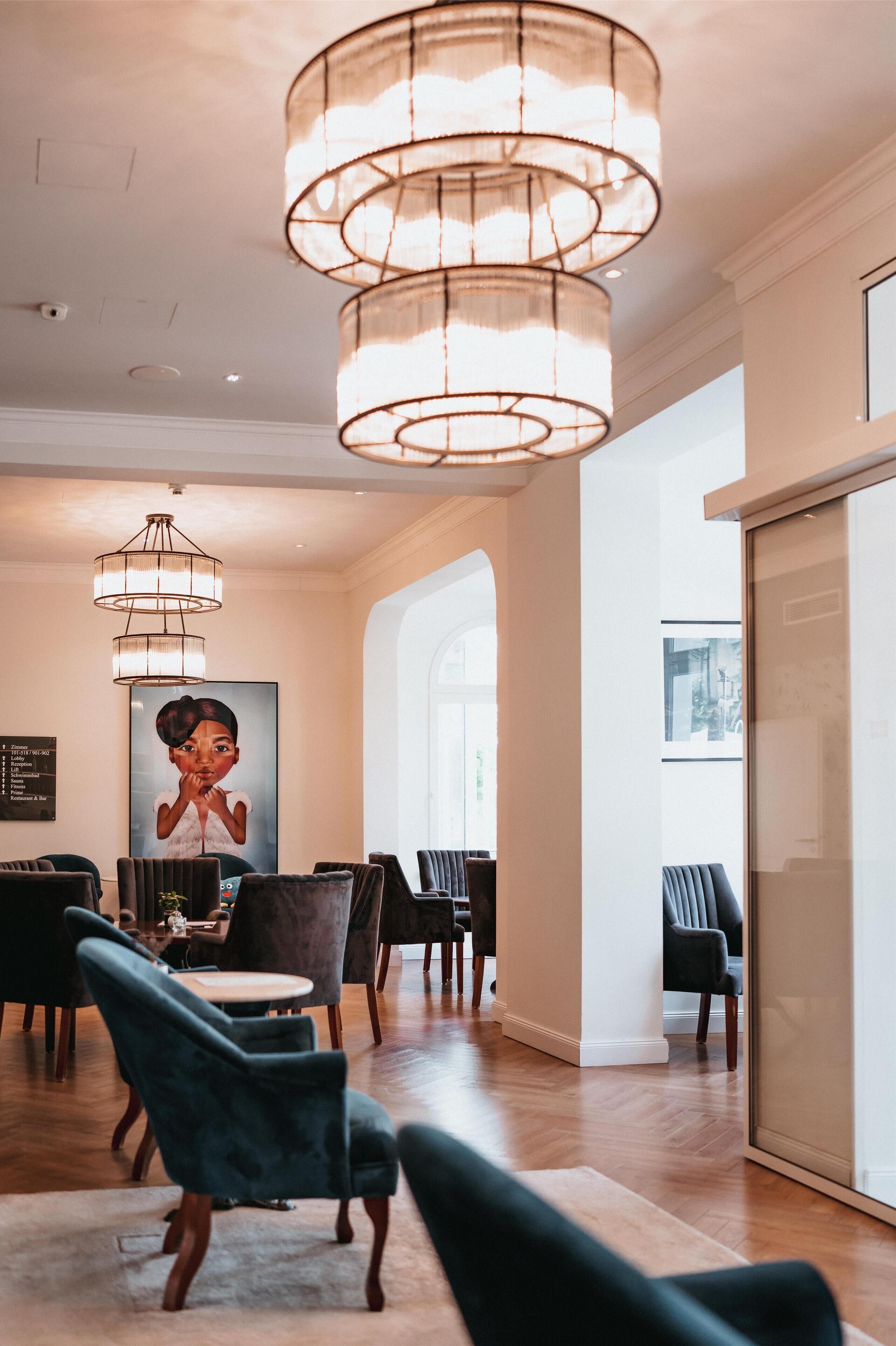 A hotel lobby with a dining area, chandeliers, and a large window.