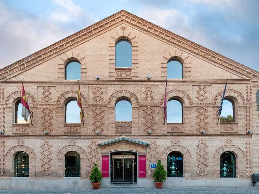 Un edificio histórico con fachada simétrica, varios ventanales de arco y una entrada central.
