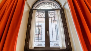 A door with a wrought iron gate and white curtains. - Hotel San Juan de los Reyes (Toledo)