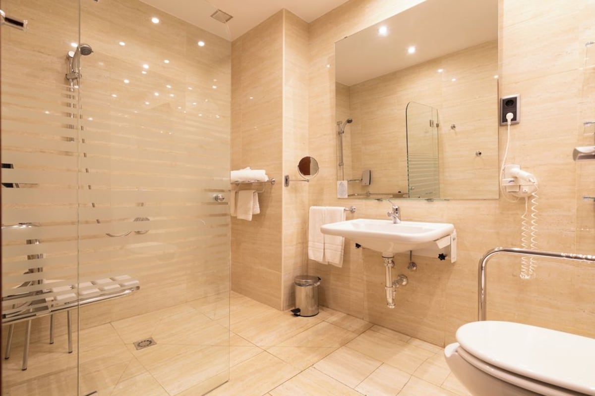 Un baño moderno con cabina de ducha de vidrio, lavamanos e inodoro.