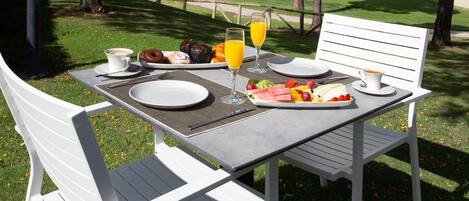 An outdoor dining table with breakfast items, a golf course in the background.