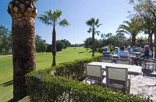An outdoor seating area with tables and chairs, overlooking a golf course.