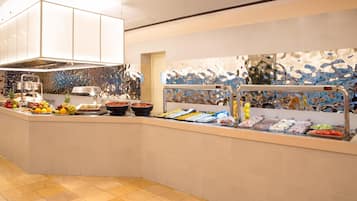 A buffet area with a variety of food items, a stainless steel sink, and a decorative backsplash.