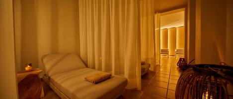 A hotel room with a bed, a nightstand, a lamp, and a wicker chair.