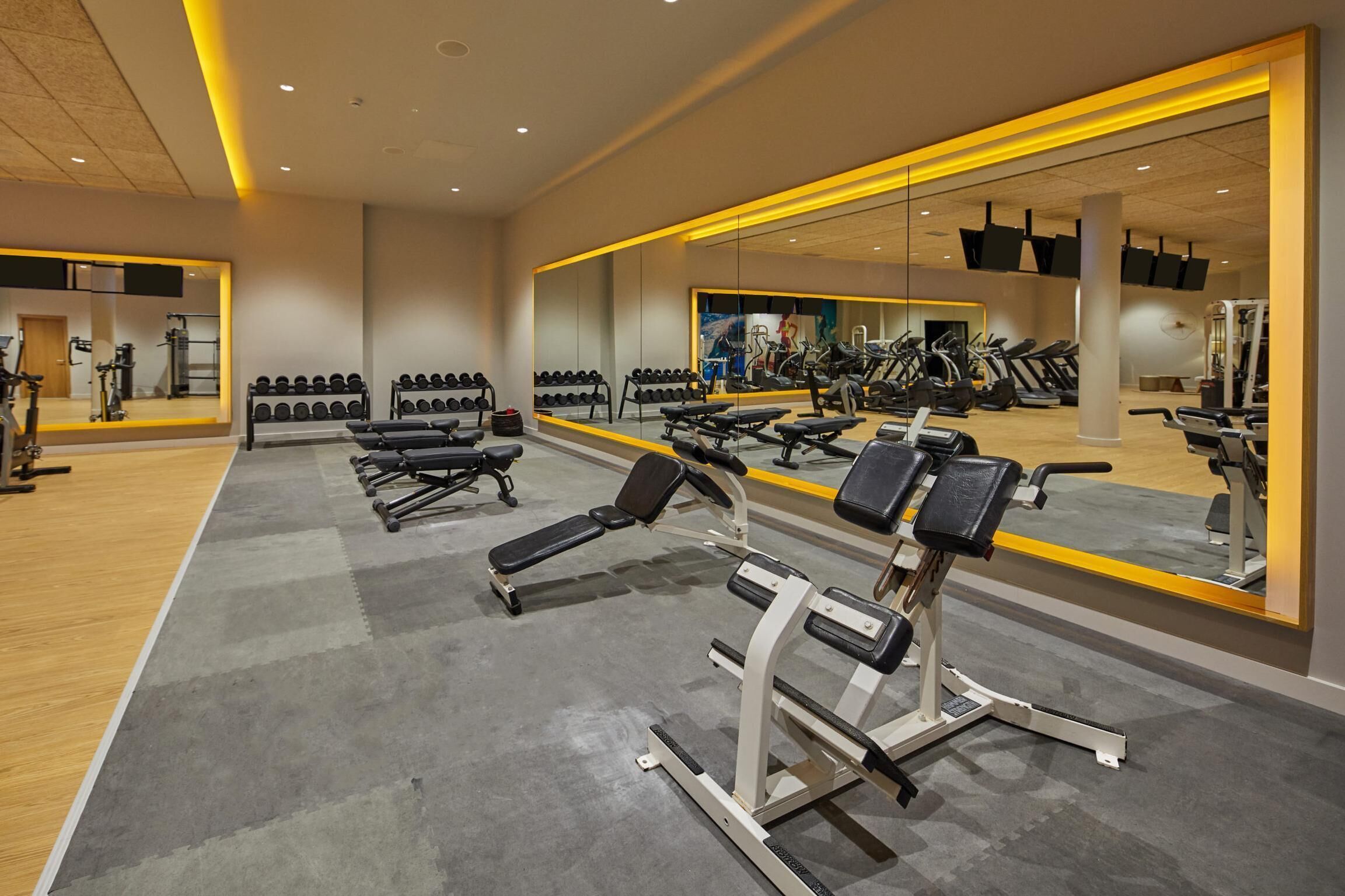 Ein modernes Fitnessstudio mit Trainingsgeräten, Spiegeln und Holzboden.