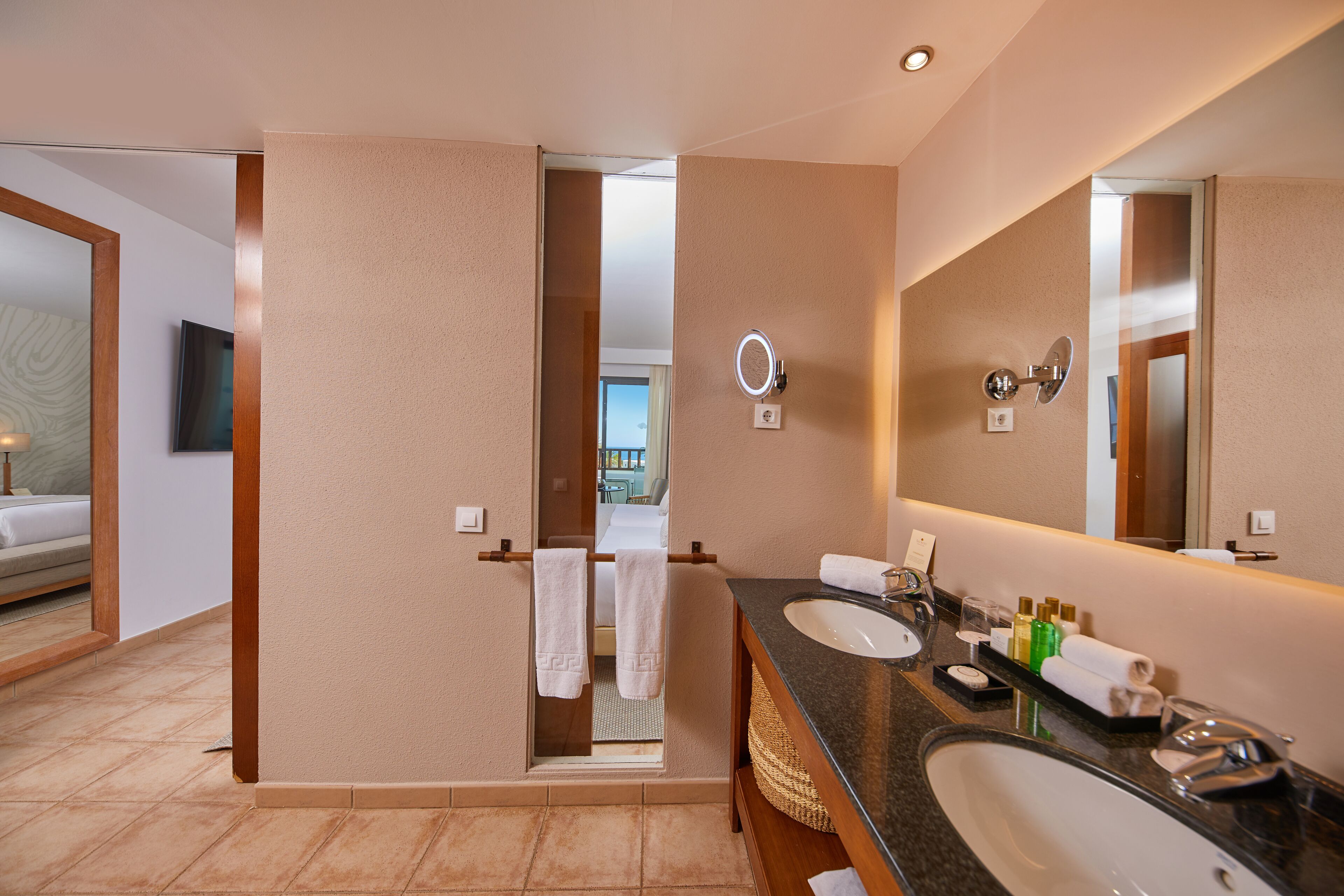 A hotel bathroom with a large mirror, two sinks, and a towel rack.