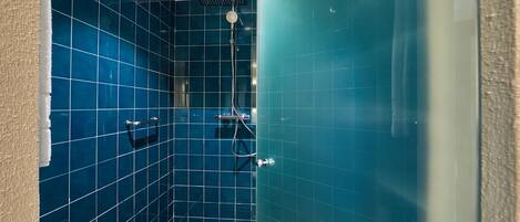 A bathroom with blue tiled walls and a shower area.