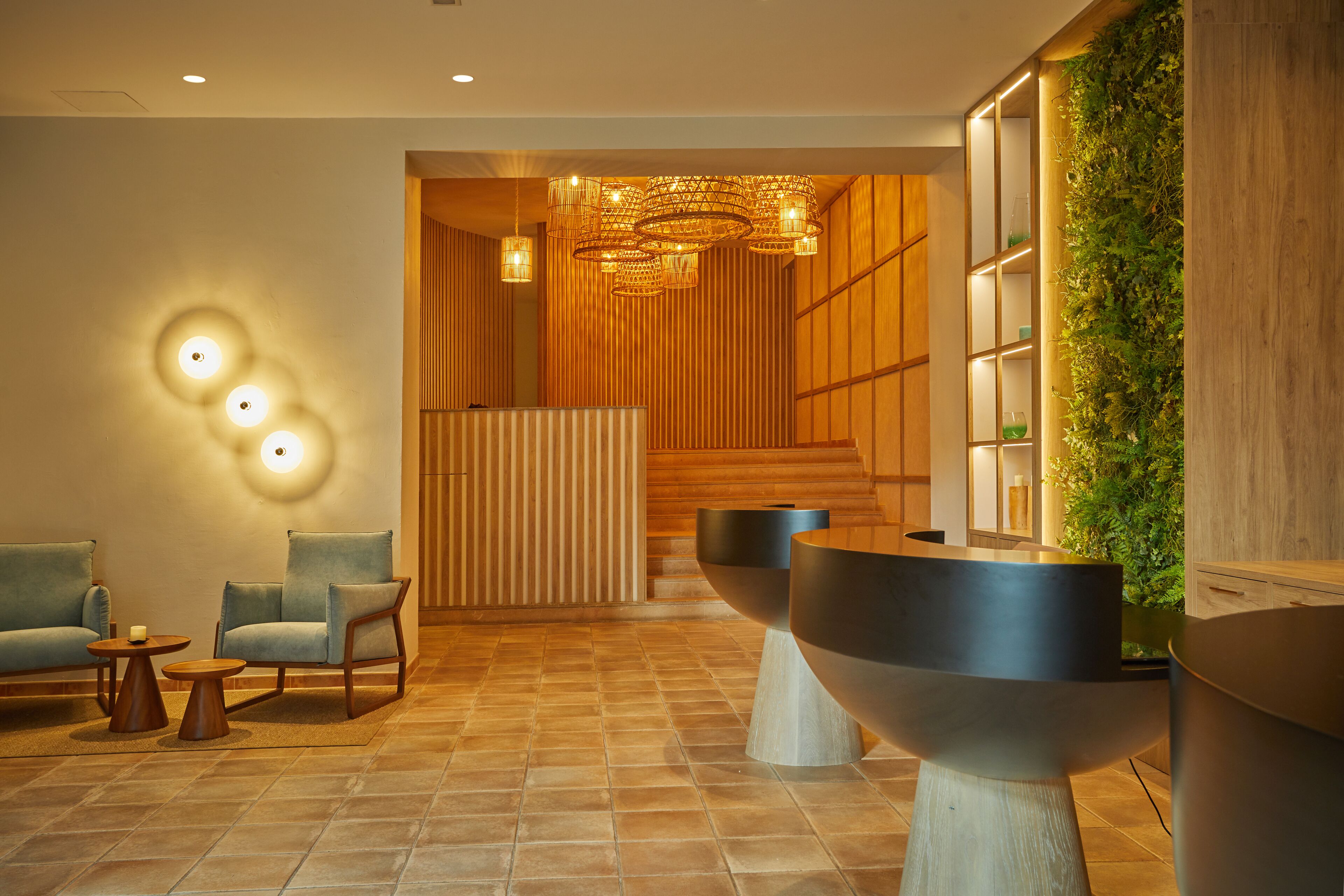 A modern lobby with a reception desk, seating area, and a decorative wall with greenery.