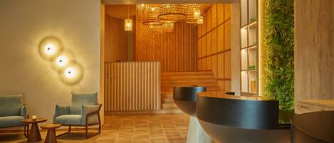 A modern lobby with a reception desk, seating area, and a decorative wall with greenery.