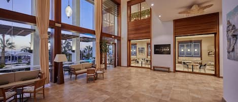 A spacious lobby with high ceilings, large windows, and a modern interior design.