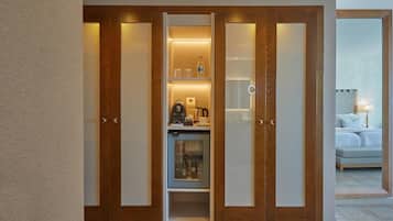 Une chambre d’hôtel avec une armoire en bois, un minibar équipé d’une machine à café et un lit avec une table de chevet.