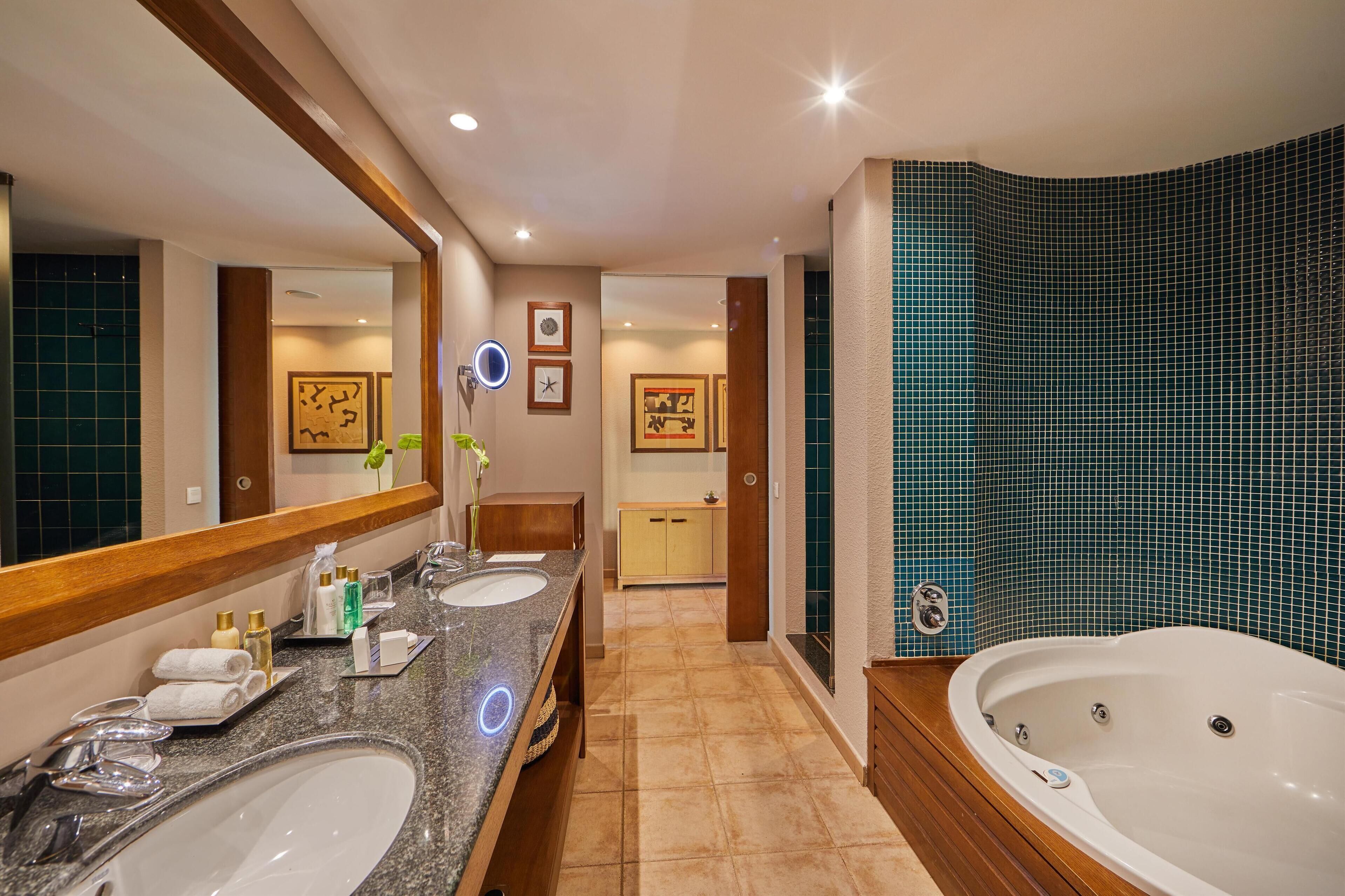Un baño moderno con dos lavamanos, un espejo grande, una bañera y un tocador con espejo.