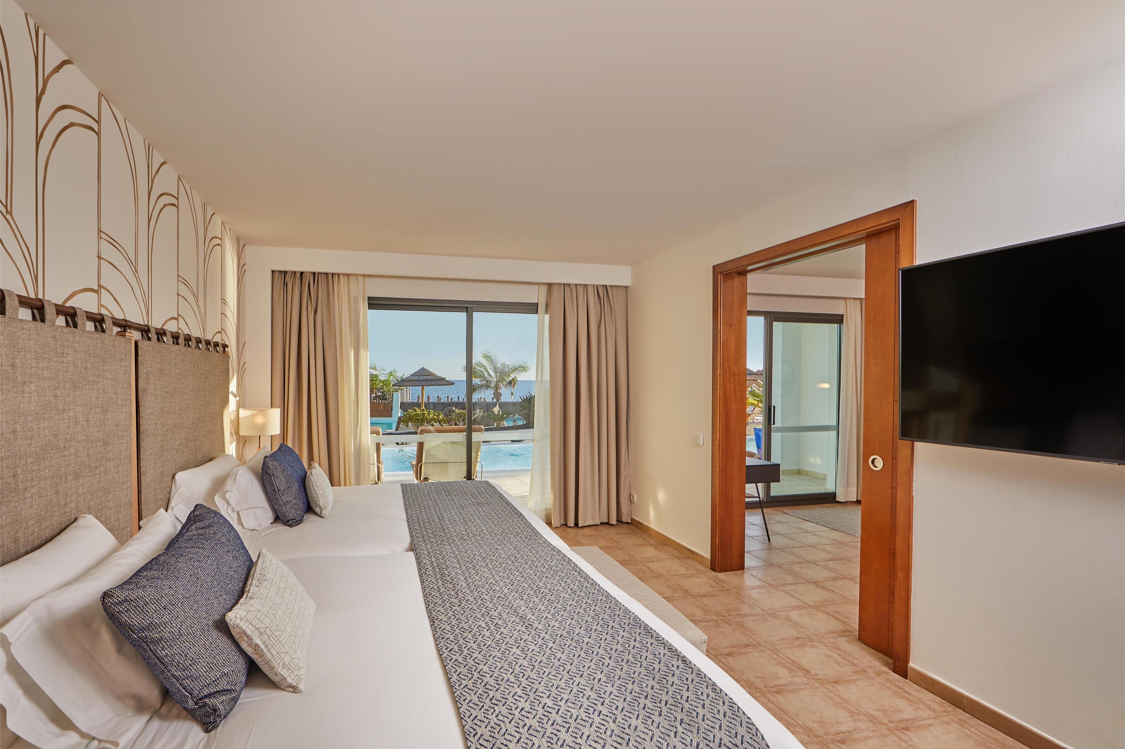 A hotel room with a large bed, a TV, and a view of a swimming pool.