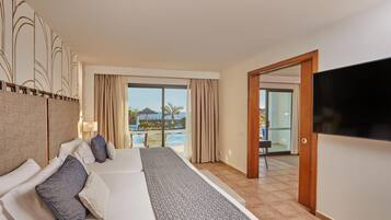 A hotel room with a large bed, a TV, and a view of a swimming pool.