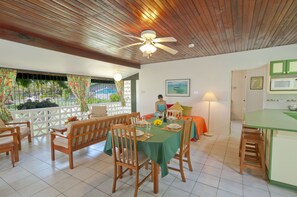 A dining area with a table set for four, wooden chairs, and a ceiling fan. - Lance Aux Epines Cottages (St. George's)