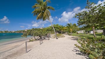 Di pantai, pasir putih, kursi berjemur, dan payung pantai