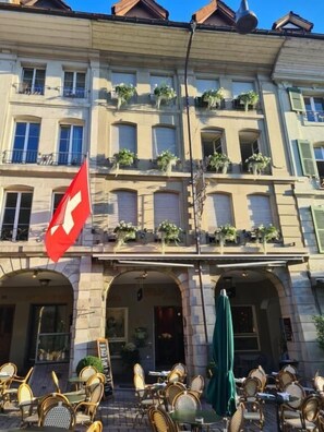 A building with multiple balconies, outdoor seating, and a Swiss flag. - Boutique Hotel Belle Epoque (Bern)