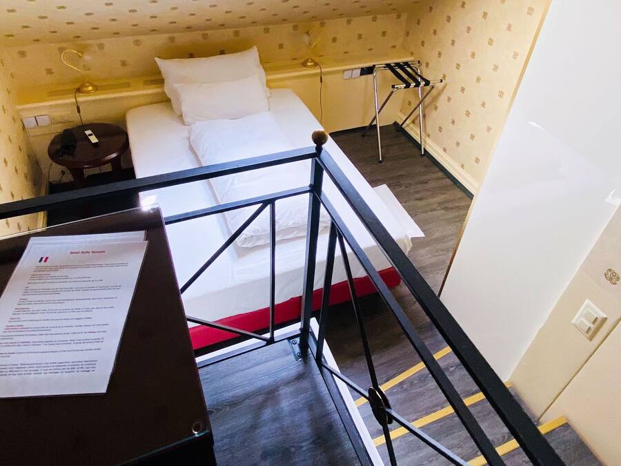 Una habitación pequeña con cama, escritorio y tragaluz.