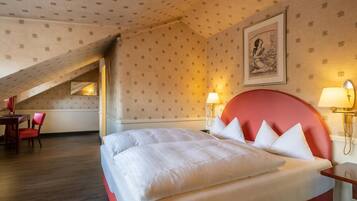 Una habitació d'hotel amb un llit gran, una taula de treball i una cadira. Hi ha un quadre a la paret i una làmpada sobre la taula de nit.