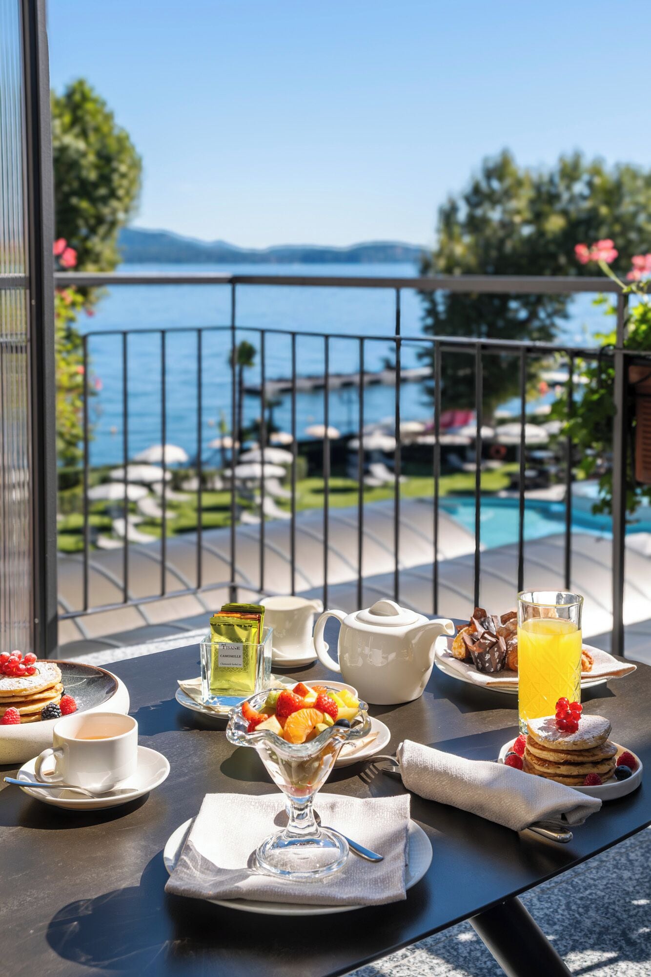 A breakfast table with a view of a pool and mountains.