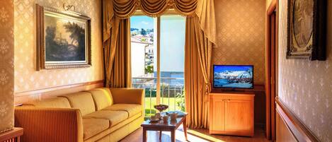 A living room with a sofa, a television, and a balcony with curtains.