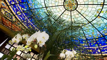 Un techo de vitrales con diseños intrincados y orquídeas blancas.